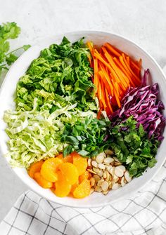 a white bowl filled with lettuce, carrots and other vegetables