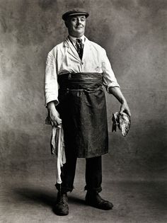 black and white photograph of a man wearing an apron, hat, and holding a baseball glove