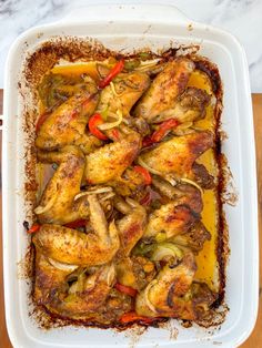 a casserole dish with chicken, peppers and onions in it on a wooden table