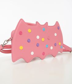 This adorable bag features a playful design of a pink circus cookie in the shape of a bat, complete with rainbow sprinkle dots for an extra sweet touch. With a convenient top handle and removable adjustable strap, you can carry this bag however you like. The inside is lined with vibrant purple and pink striped fabric, along with two slip pockets and one zipper pocket for all your essentials.Available while supplies last. Fun Pink Shoulder Bag With Adjustable Strap, Fun Pink Party Bags, Pink Novelty Bags For Everyday Use, Playful Pink Shoulder Bag With Adjustable Strap, Pink Novelty Bag For Everyday Use, Playful Pink Bag With Adjustable Strap, Playful Pink Shoulder Bag, Playful Pink Party Bag, Kawaii Multicolor Bag With Zipper Closure