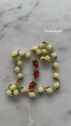 the beaded bracelet is made with white flowers and green leaves, on a marble surface