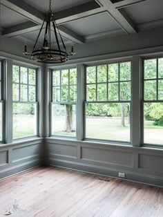 an empty room with large windows and wood floors