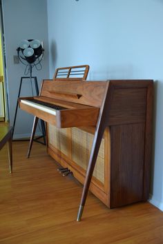 an old wooden piano sitting on top of a hard wood floor next to a wall