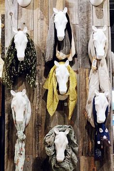 several horse heads mounted to the side of a wooden wall