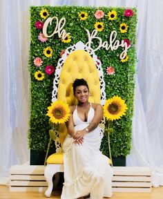 a woman sitting on a yellow chair with sunflowers in front of a backdrop