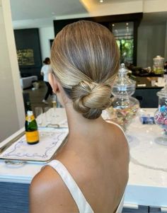 a woman with blonde hair in a low bun sitting at a counter looking into the distance