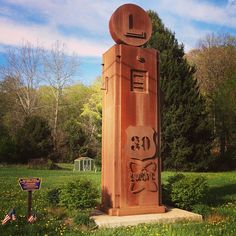 there is a large statue in the middle of a field with trees and bushes behind it