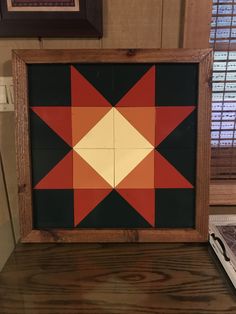 a wooden frame with an orange and black star pattern on the inside, sitting on top of a table