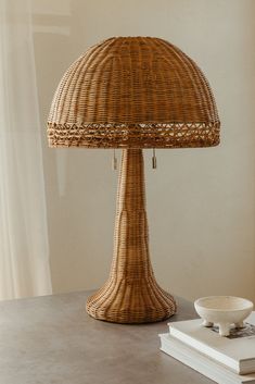 a wicker lamp sitting on top of a table next to a book and bowl