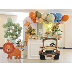 an animal themed birthday party with balloons and decorations on the wall, including a safari car