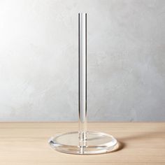 a clear glass stand on a wooden table with a white wall in the back ground