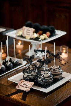 there are many desserts on the table and one is chocolate cake pops with black icing