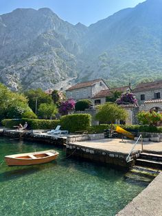 there is a boat that is sitting in the water next to some houses and mountains