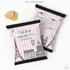 two pink and black bags with paris themed designs on them, next to a cookie