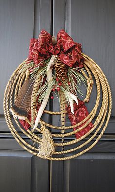 a wreath made out of rope with feathers and other items hanging on the front door