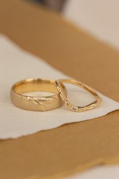 two gold wedding rings sitting on top of a piece of paper next to each other