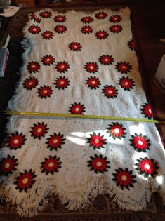 a white blanket with red flowers on it and a measuring tape in front of it