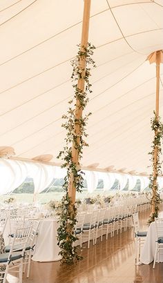 the inside of a large tent with tables and chairs set up for an outdoor wedding