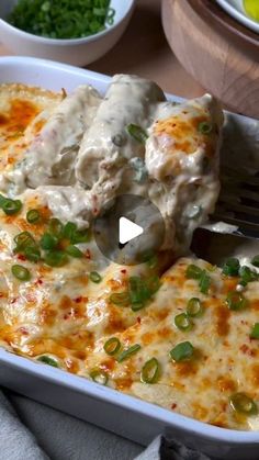 a white casserole dish with green onions and cheese on it, being held by a fork