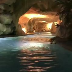 the pool is surrounded by large rocks and palm trees, with water flowing from it