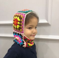 a young child wearing a crocheted hat and scarf