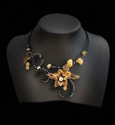 a black and gold necklace on a mannequin with beads in the shape of flowers