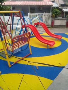 an empty playground with swings and slides in the middle, on a blue yellow and red painted area