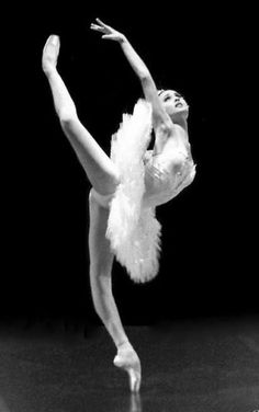 a ballerina in white tutu and feathered skirt doing a ballet move with her arms stretched out