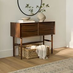 a wooden dresser sitting next to a mirror and basket on top of a table with flowers in it