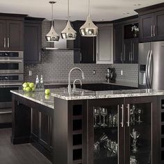 a kitchen with dark wood cabinets and marble counter tops, stainless steel appliances and an island in the middle