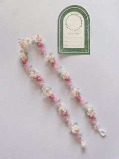 two pieces of string with flowers on them next to a tag