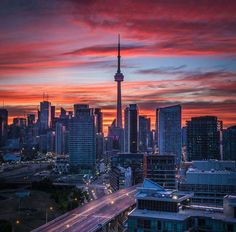 the city skyline is lit up at night with red and orange clouds in the sky