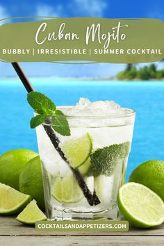 a glass with ice, limes and mint on the table next to some water