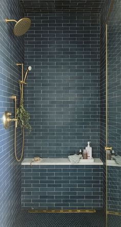 a blue tiled bathroom with gold fixtures and shower head in the corner, next to a white bathtub