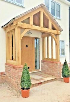 a house with two potted plants in front of it and a wooden entryway