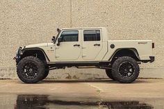 a white jeep parked in front of a building next to a puddle on the ground