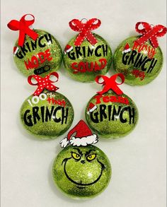 six grinch christmas ornaments with red bows and green baubles in the shape of balls