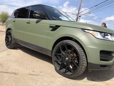 a green range rover is parked on the side of the road in front of power lines