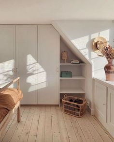 an attic bedroom with white walls and wooden flooring, built - in bookshelves