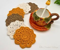 crocheted coasters are sitting on a table next to a cup and saucer