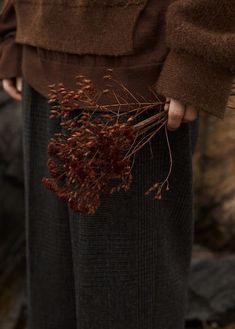 a person is holding some plants in their hands while standing next to rocks and water