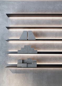 an abstract sculpture is displayed in front of a concrete wall with shelves and lights on it