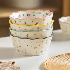 four different colored bowls sitting on top of a table next to plates and utensils