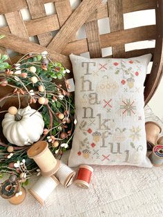 a wooden chair with a pillow and some spools of thread on top of it