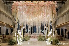 the entrance to a wedding venue decorated in pink and white flowers with hanging chandeliers