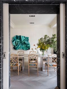 a dining room table with chairs and a large green painting on the wall behind it