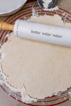 rolling dough on top of a red and white plate with a rolling pin next to it