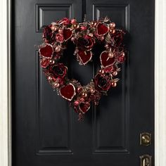 a heart shaped wreath is hanging on the front door