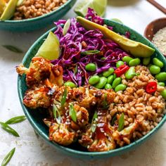 two bowls filled with rice, meat and veggies on top of a table