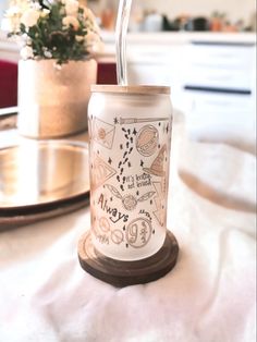 a glass with a straw in it sitting on a table next to a potted plant